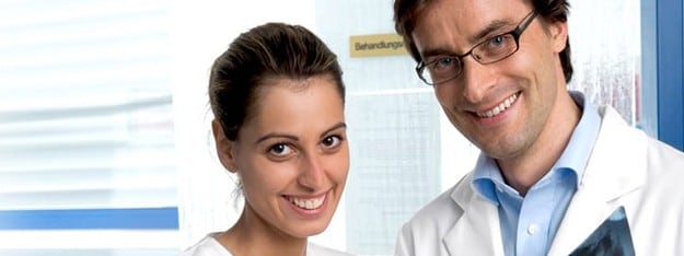Two smiling dental professionals in white lab coats standing in a bright clinic, representing expert care and cavity prevention services