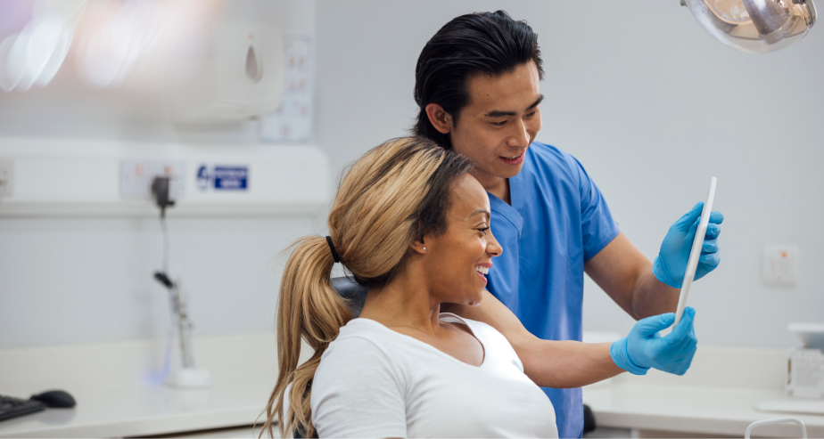 Dentista mostrando resultados en una tableta a su paciente sonriente durante una consulta odontológica en una clínica dental