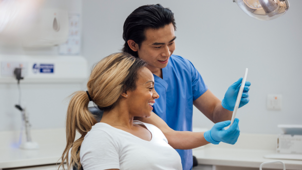 Dentista mostrando resultados en una tableta a su paciente sonriente durante una consulta odontológica en una clínica dental
